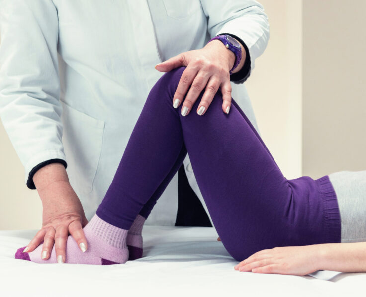 Physical therapist working with little girl on therapy bed